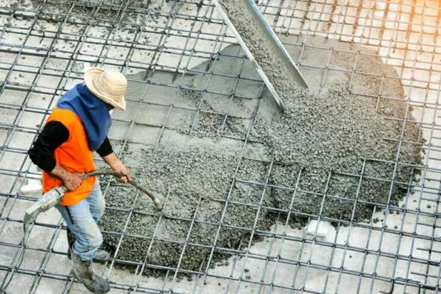 Worker directing concrete placement over a reinforcement grid