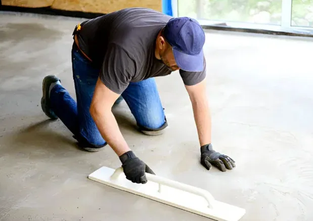 Worker using a hand float to finish a concrete slab